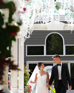 Bride and groom walking candidly through an archway at Giorgio’s Baiting Hollow during wedding portraits