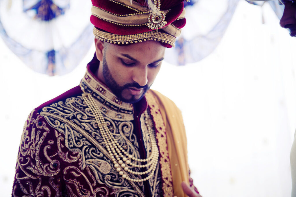 Candid portrait of a South Asian groom on his wedding day in traditional attire.