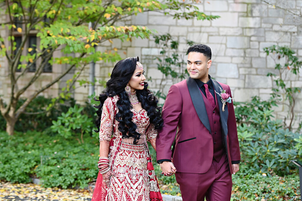 Bride and groom walking romantically at Planting Fields Arboretum in traditional wedding clothing on Long Island.