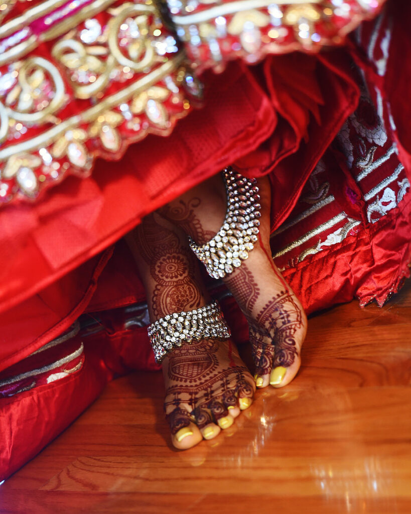 Hindu wedding ceremony bridal feet detail with anklets beneath red lehenga