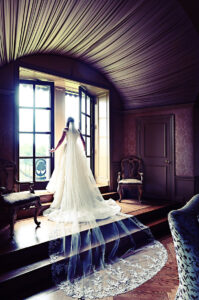 Bride photographed in the bridal suite window at Oheka Castle during wedding day preparations