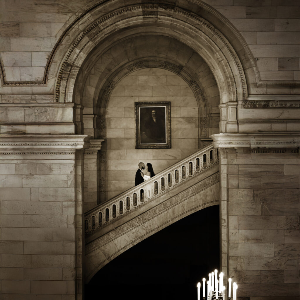 Engaged couple posing on the grand stairs during an engagement portrait at the New York Public Library.
