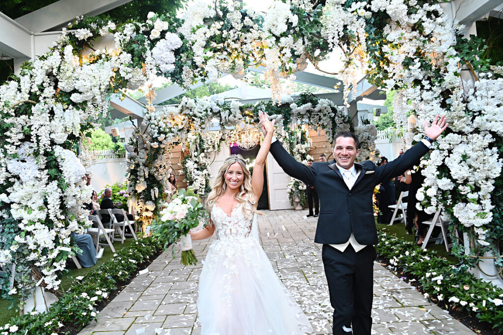 storytelling wedding photography of couple celebrating ceremony exit under floral canopy