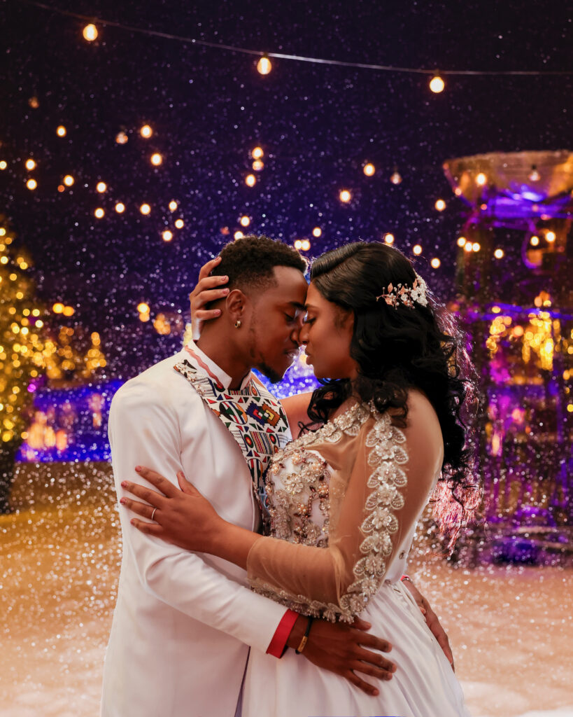 African American bride and groom embracing during a snowy winter wedding at Crest Hollow Country Club, surrounded by falling snow and soft winter light.