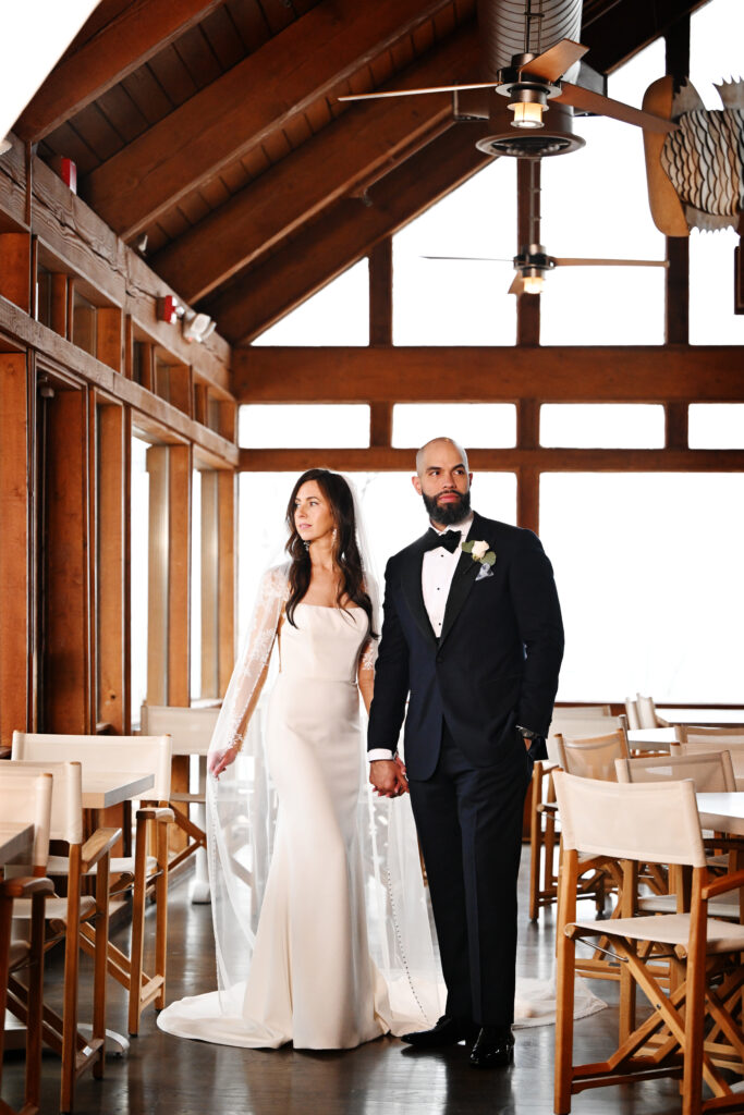 Bride and groom standing together under wooden beams at Crescent Beach Club wedding venue Long Island New York
