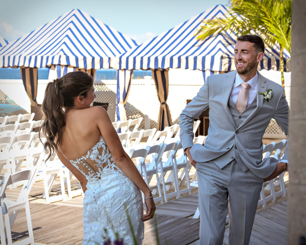 Groom first reveal smiling near striped cabanas at Crescent Beach Club wedding Long Island New York