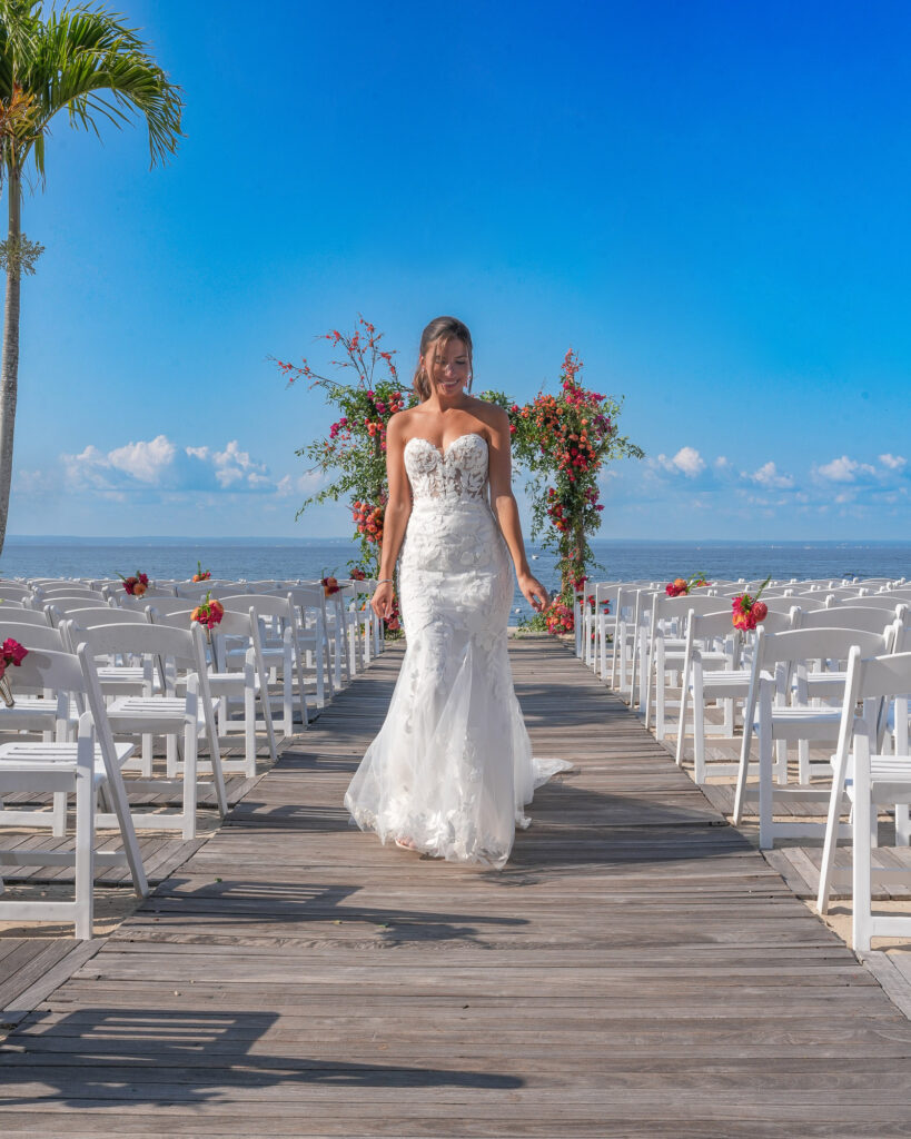 Bride walking down the aisle toward floral arch at Crescent Beach Club beach wedding Long Island New York