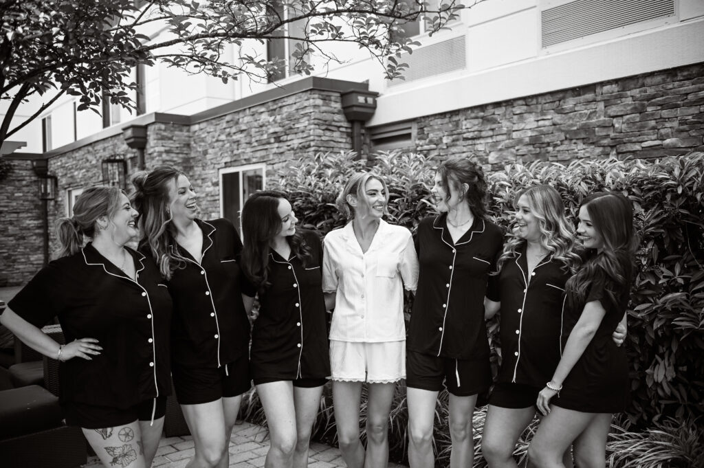 Black and white bridesmaids group portrait at Crescent Beach Club, Long Island, New York near a stone wall.