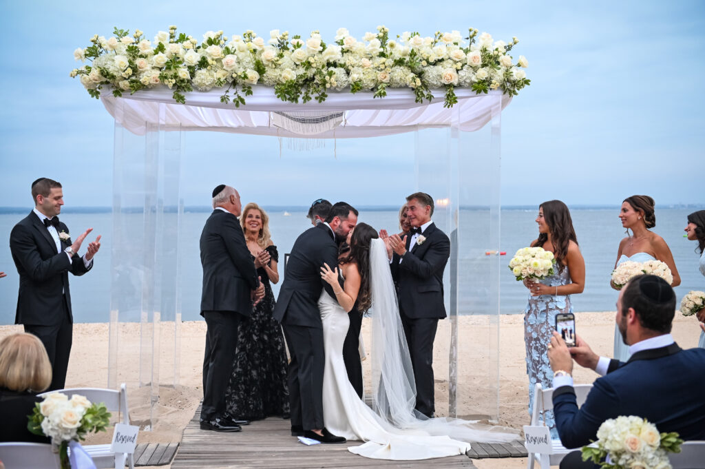 Jewish Wedding ceremony on the beach under a floral chuppah at Crescent Beach Club, Long Island, New York.
