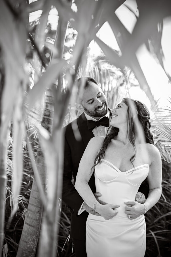 Black and white candid wedding portrait at Crescent Beach Club on Long Island, New York framed by foliage.
