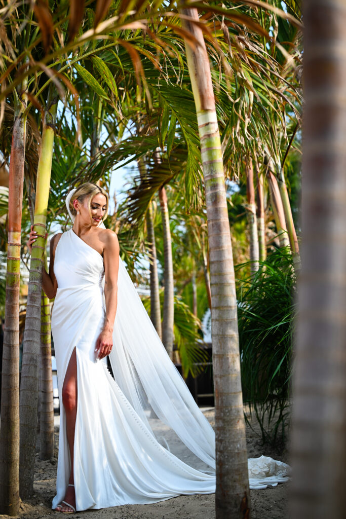 Bride standing among palm trees at Crescent Beach Club wedding venue on Long Island, New York.