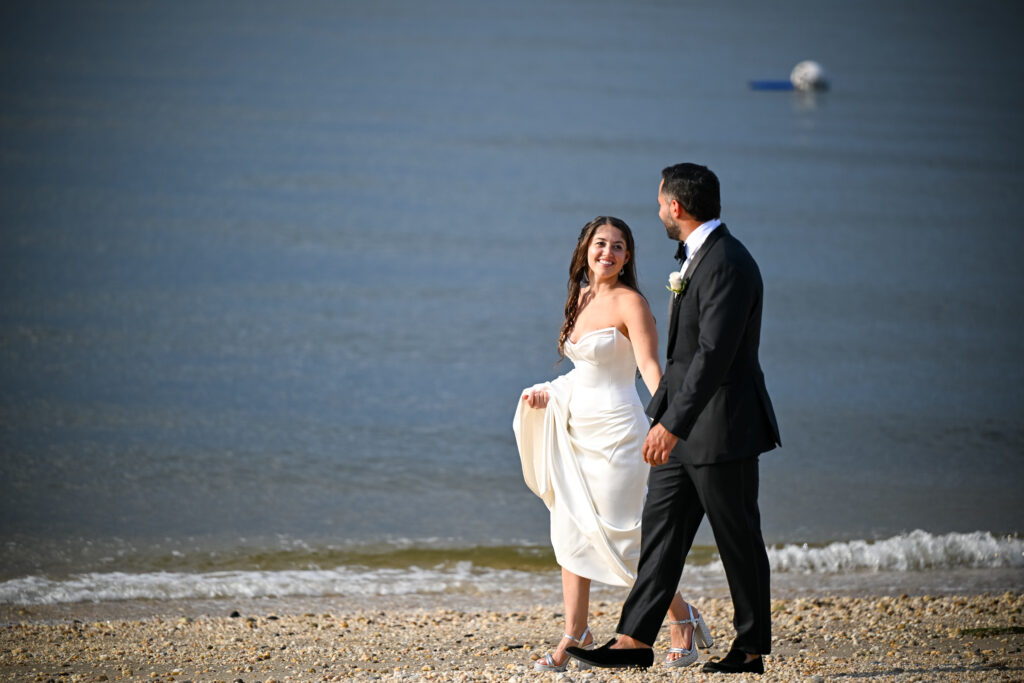 Bride and groom walk along the shoreline at Crescent Beach Club wedding in Long Island, New York.