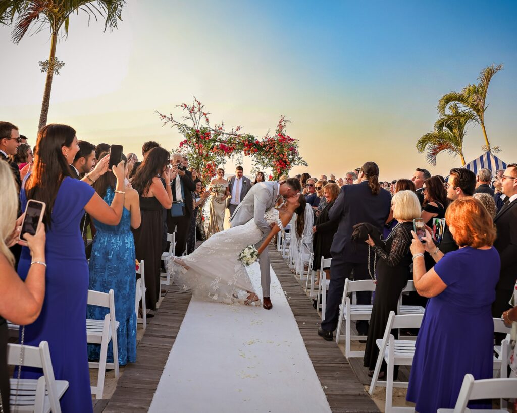 Crescent Beach Club wedding photo at Bayville, Long Island, New York: crescent beach club wedding aisle dip kiss crowd cheering. Photo by Doug Gordon | Patken Photographer.