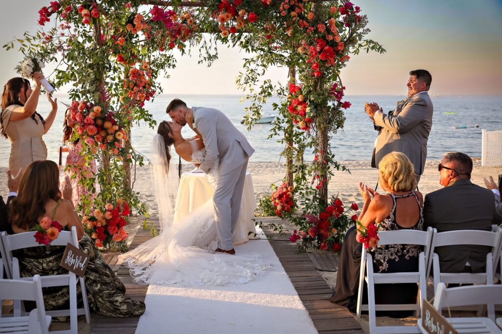 Crescent Beach Club wedding photo at Bayville, Long Island, New York: crescent beach club wedding recessional cheer under floral arch. Photo by Doug Gordon | Patken Photographer.