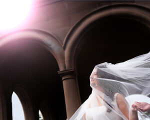 Bride alone with veil blowing over her face at Coe Hall in Planting Fields Arboretum, Oyster Bay NY