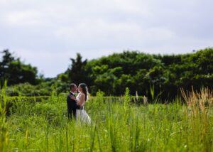 Bride and groom pose in tall grass at Jones Beach for a Gatsby-inspired wedding portrait by Doug Gordon of Patken Photographer