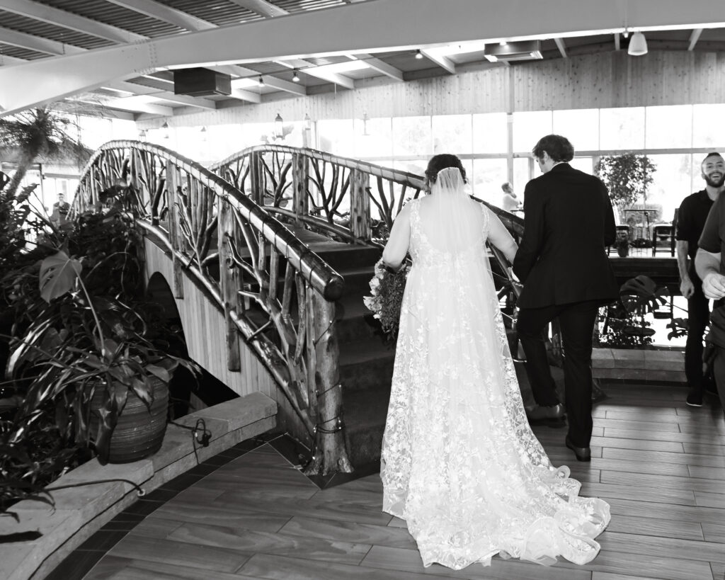 Bride and groom walking across bridge at Flowerfield St. James