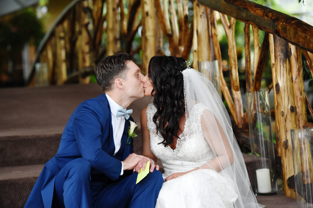 Bride and groom kissing under wooden structure at Flowerfield