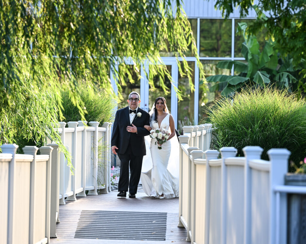 Bride and groom walking down bridge aisle at Flowerfield St. James