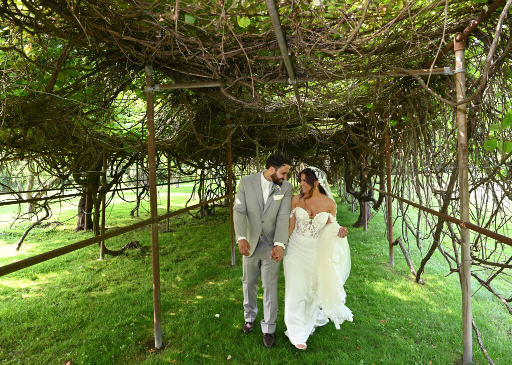 Bride and groom under vine covered arbor at Flowerfield