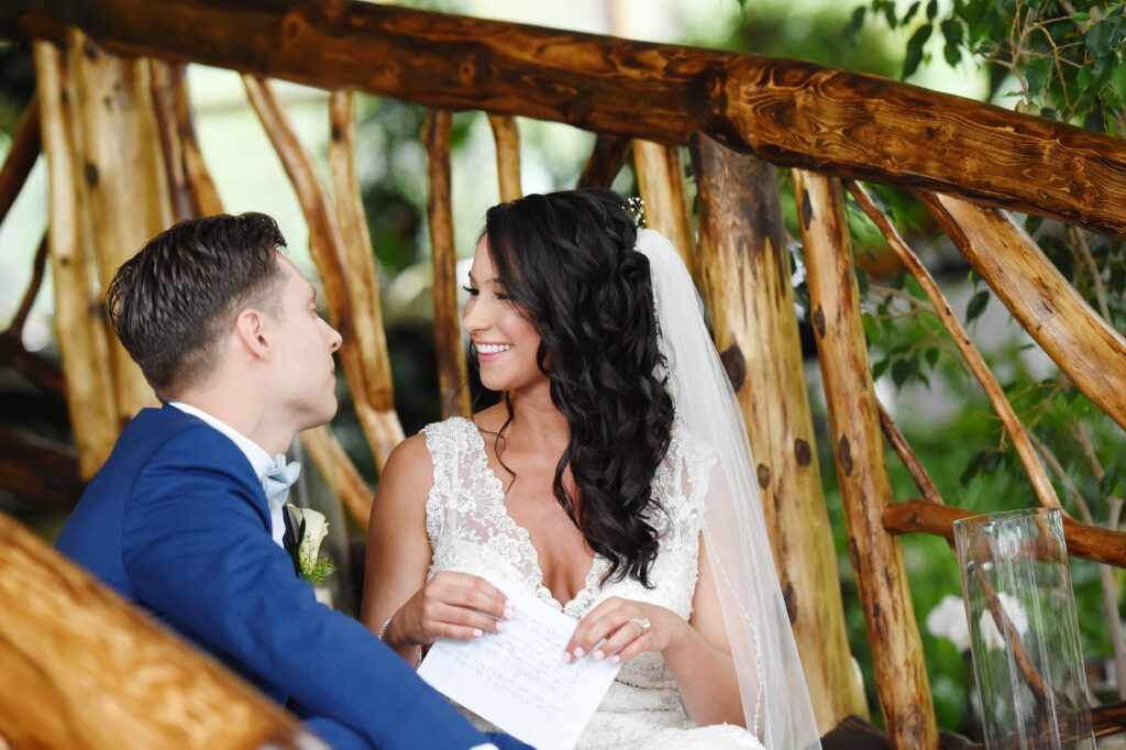 Bride and groom seated together under wooden gazebo at Flowerfield