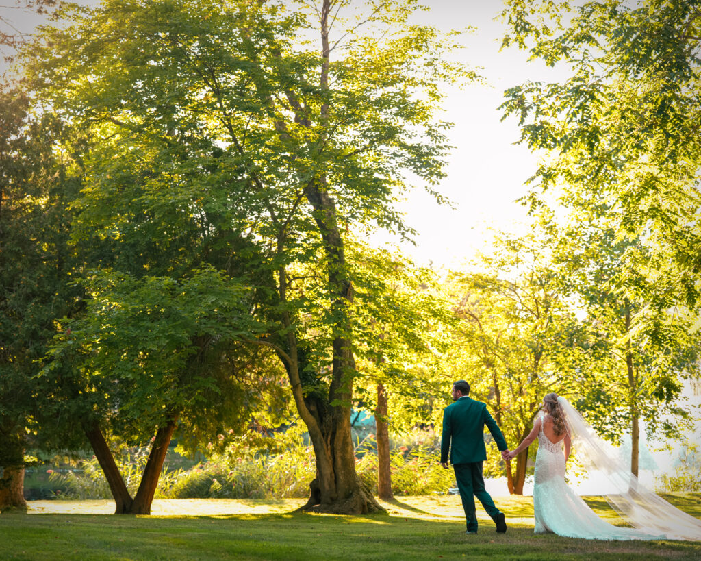 Bride and groom walking through trees at Flowerfield