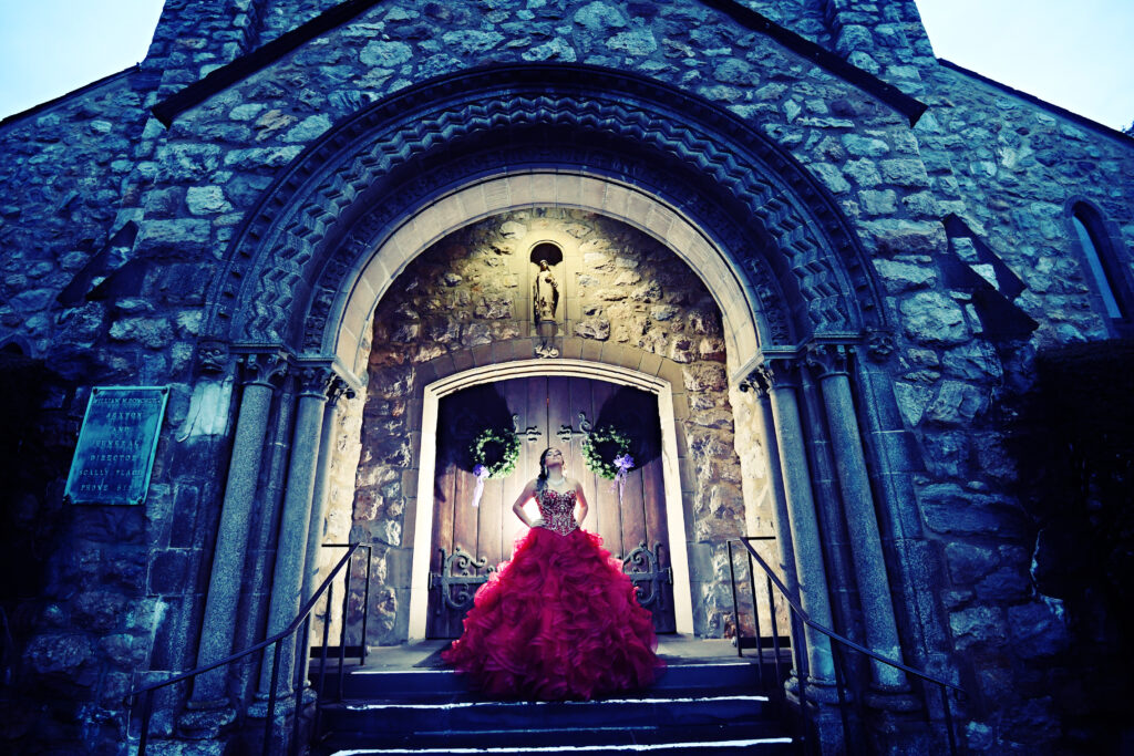 Quinceañera wearing a cathedral-style gown during a formal portrait in New York, featuring elegant architecture and refined lighting.