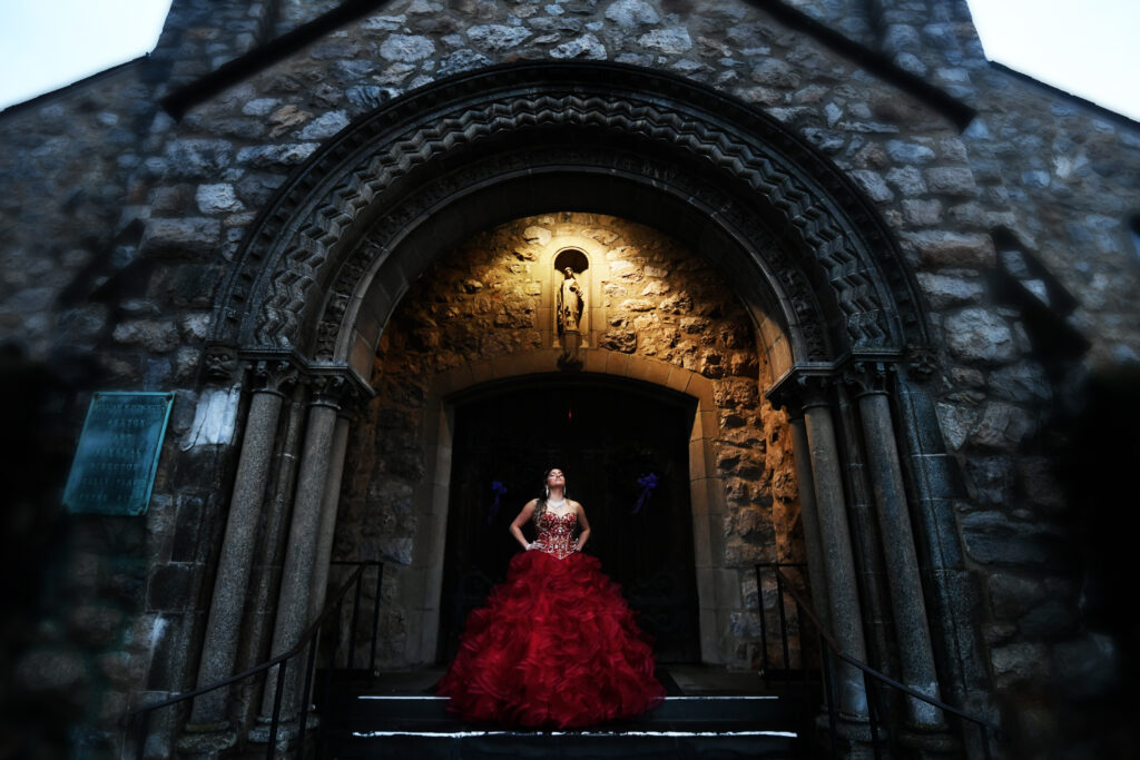 Quinceañera night portrait captured at a stone chapel in New York, featuring dramatic lighting and elegant styling.