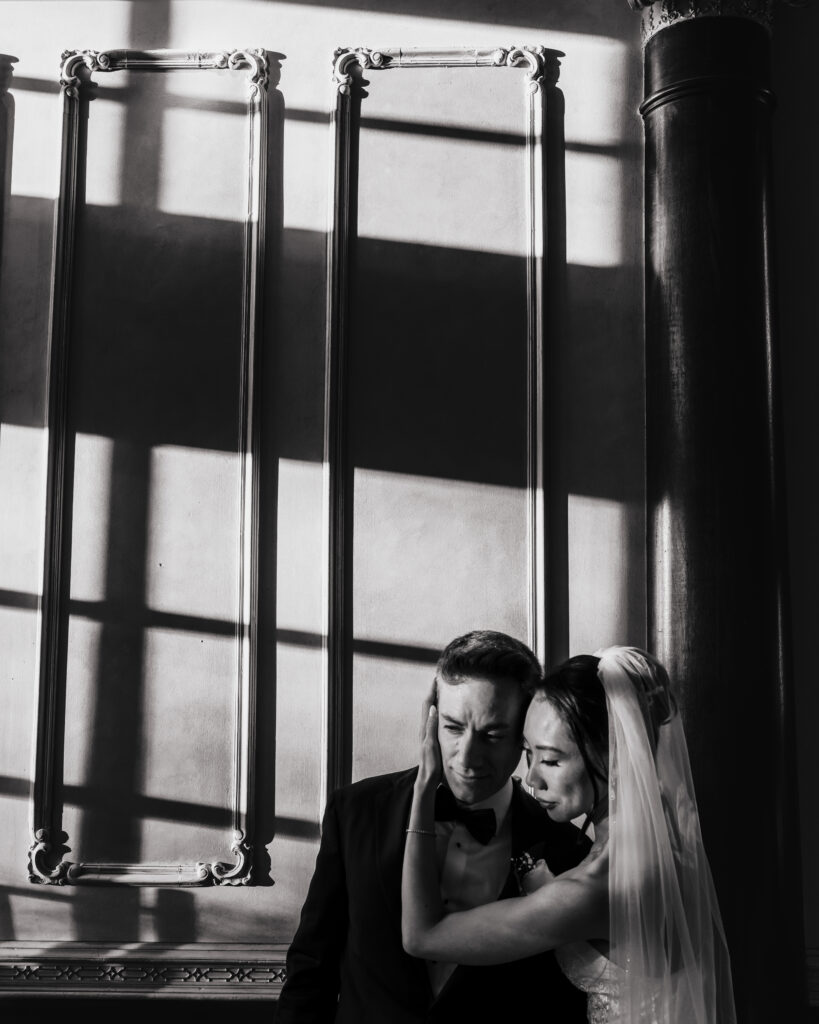 Bride and groom silhouette by large window in black and white wedding portrait Westbury manor