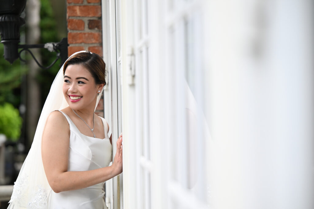 Bride portrait by window holding bouquet at Long Island wedding venue Westbury manor