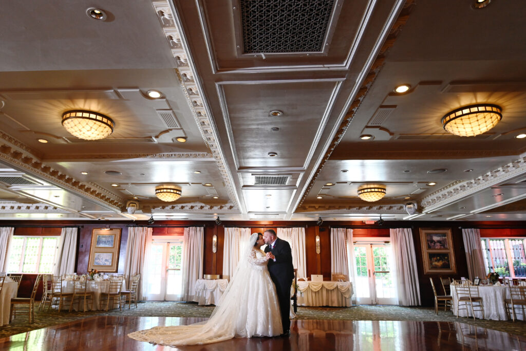 Bride and groom posing in wood-paneled ballroom at Westbury Manor wedding