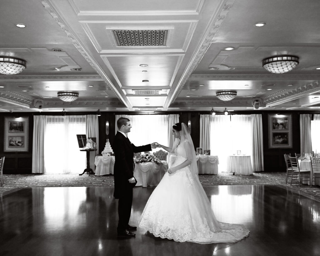 Bride and groom cutting wedding cake in Westbury Manor ballroom