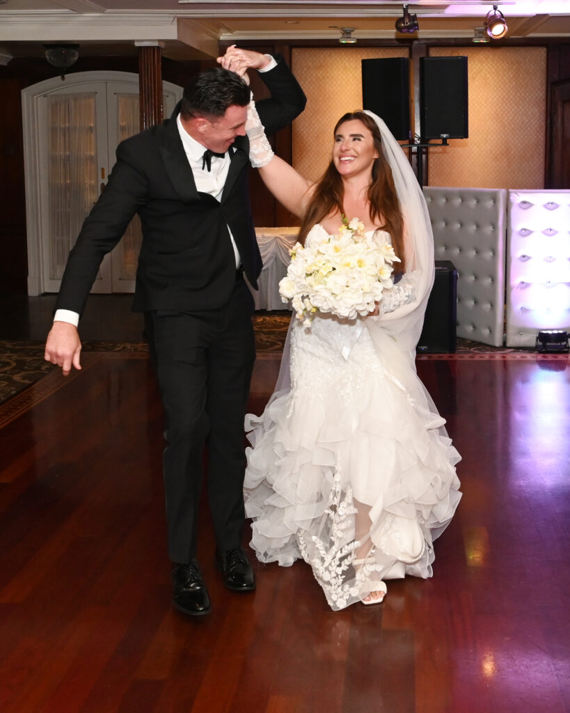 Bride and groom entering Westbury Manor ballroom reception cheering crowd