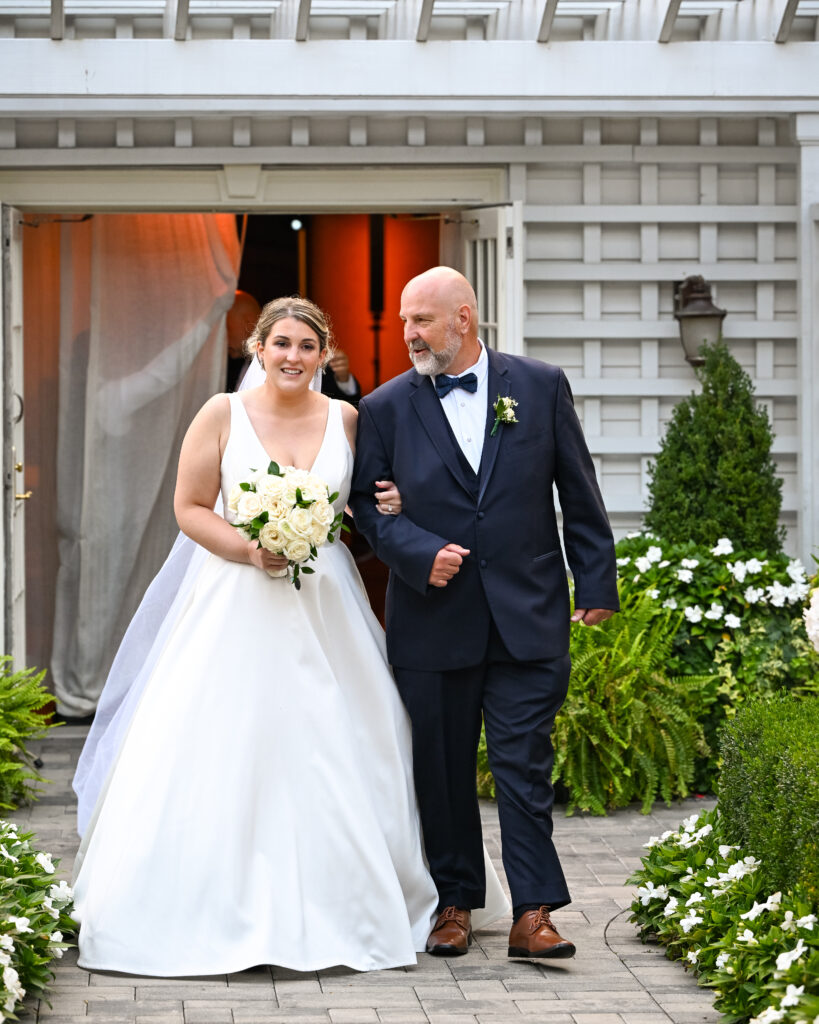 Bride walking with father outside Westbury Manor Long Island wedding venue