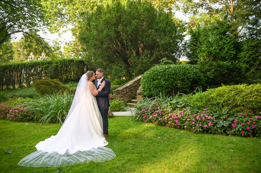Bride and groom embracing on manicured lawn at Westbury Manor Long Island