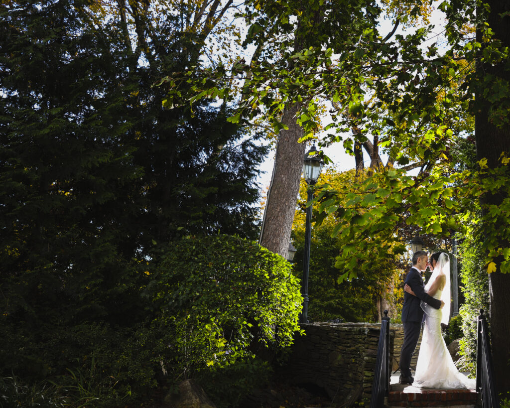 Bride and groom standing beneath trees at Westbury Manor wedding Long Island