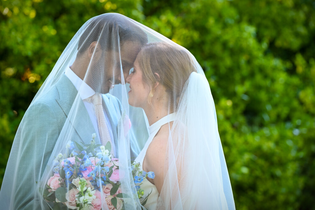 Bride and groom under veil in Westbury Manor garden Long Island