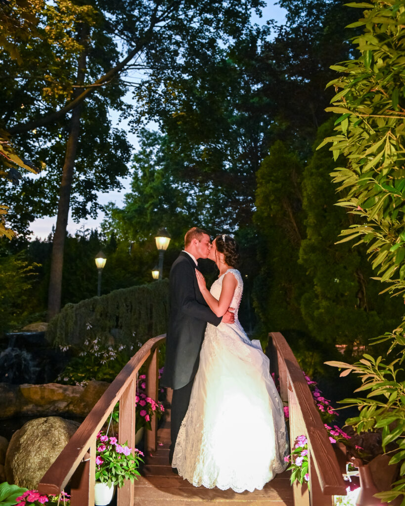 Bride and groom kissing on garden bridge at Westbury Manor wedding