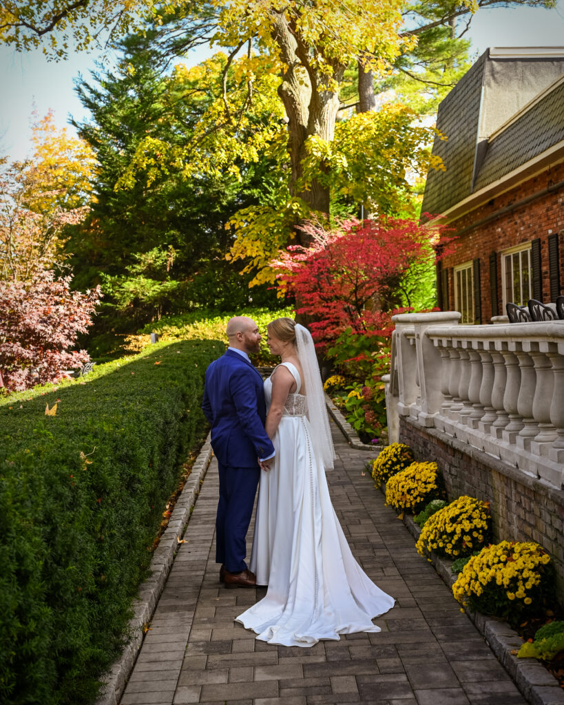 Bride and groom posing along building exterior at Westbury Manor Long Island