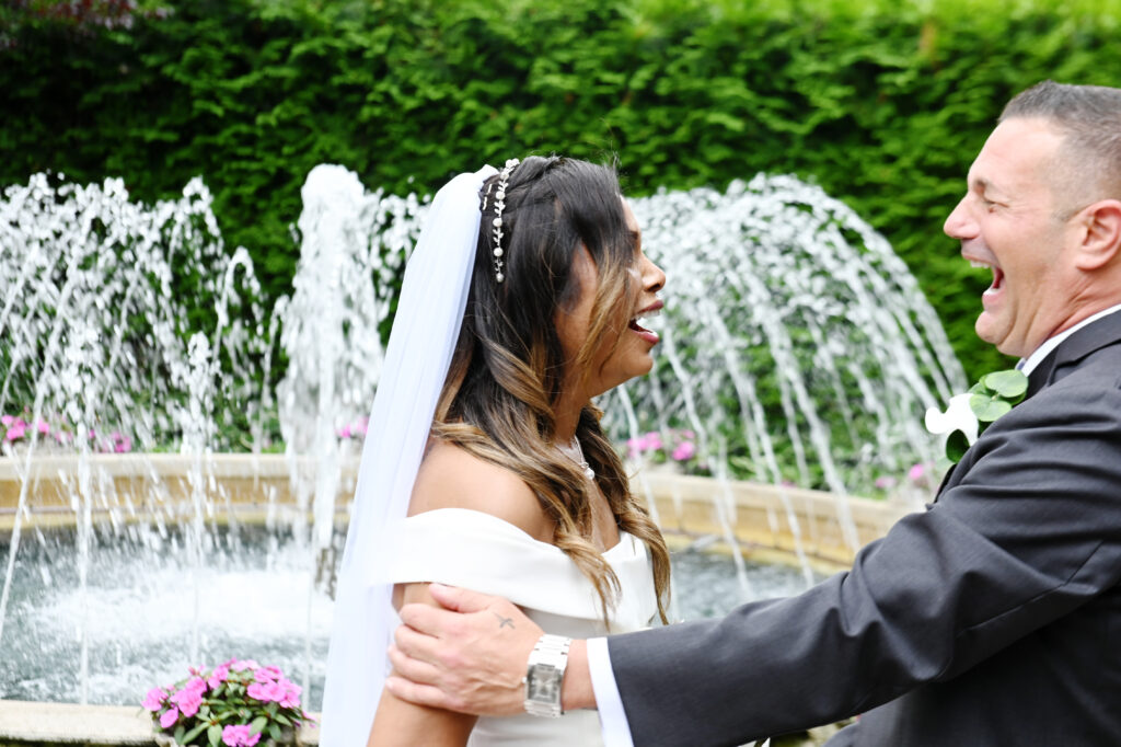 Bride smiling near garden fountain at Westbury Manor Long Island wedding