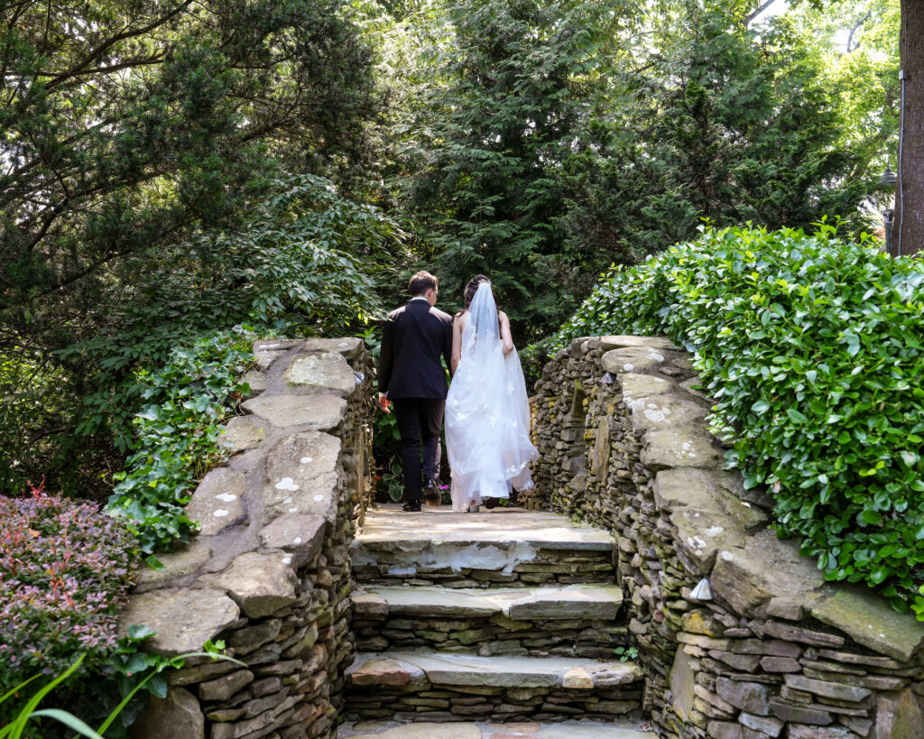 Bride and groom walking on stone staircase in Westbury Manor garden