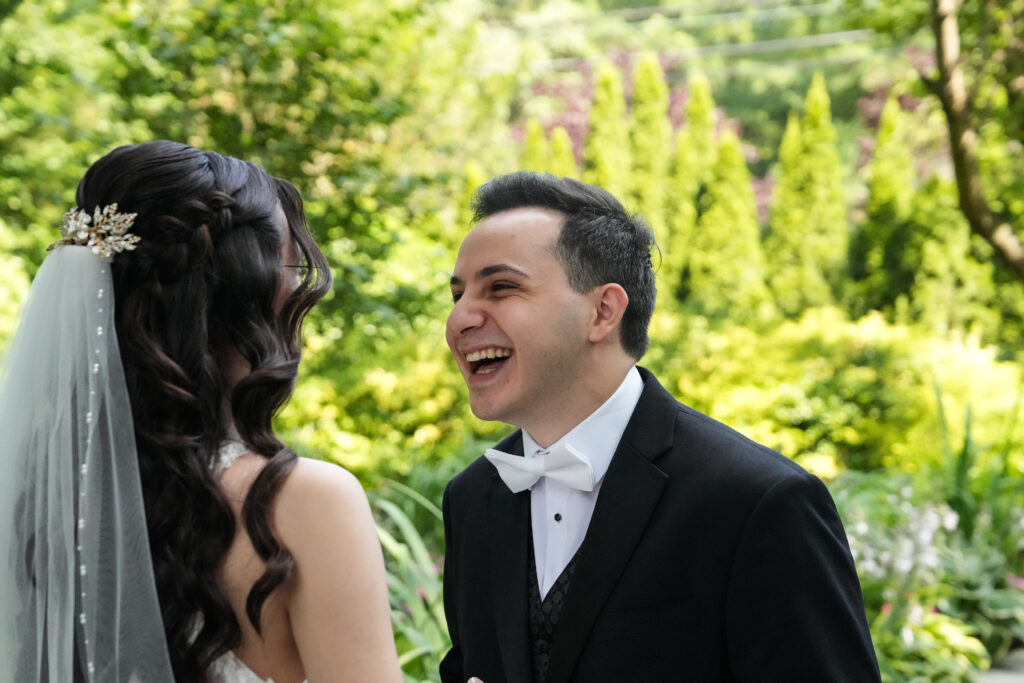 Groom laughing during outdoor wedding portrait at Westbury Manor Long Island