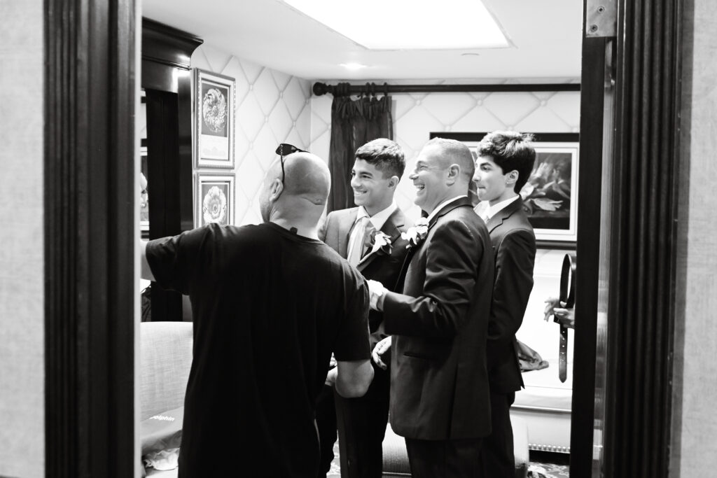 Groom adjusting tie during getting ready at Westbury Manor Long Island