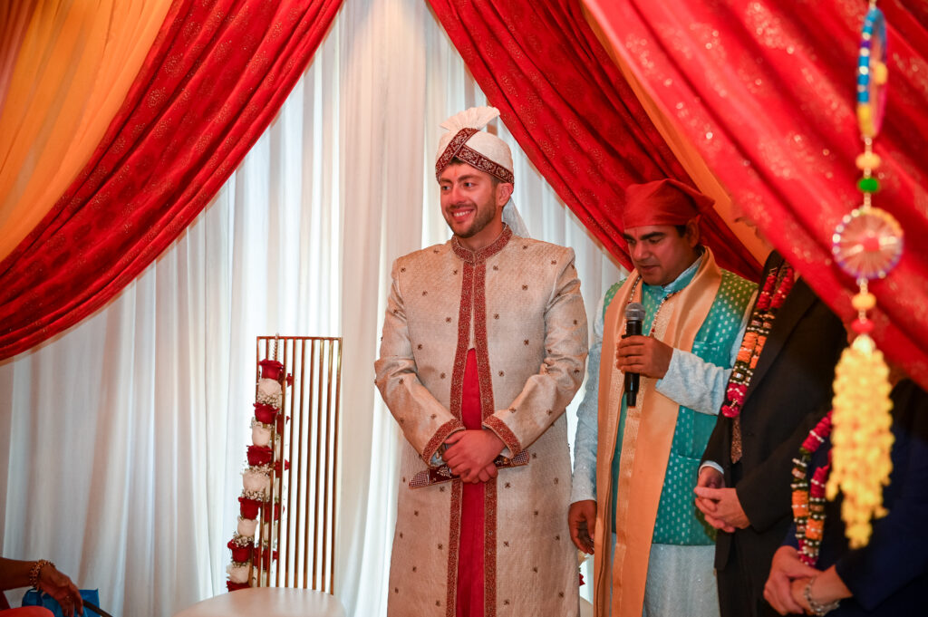 South Asian groom adjusting attire inside Westbury Manor wedding venue