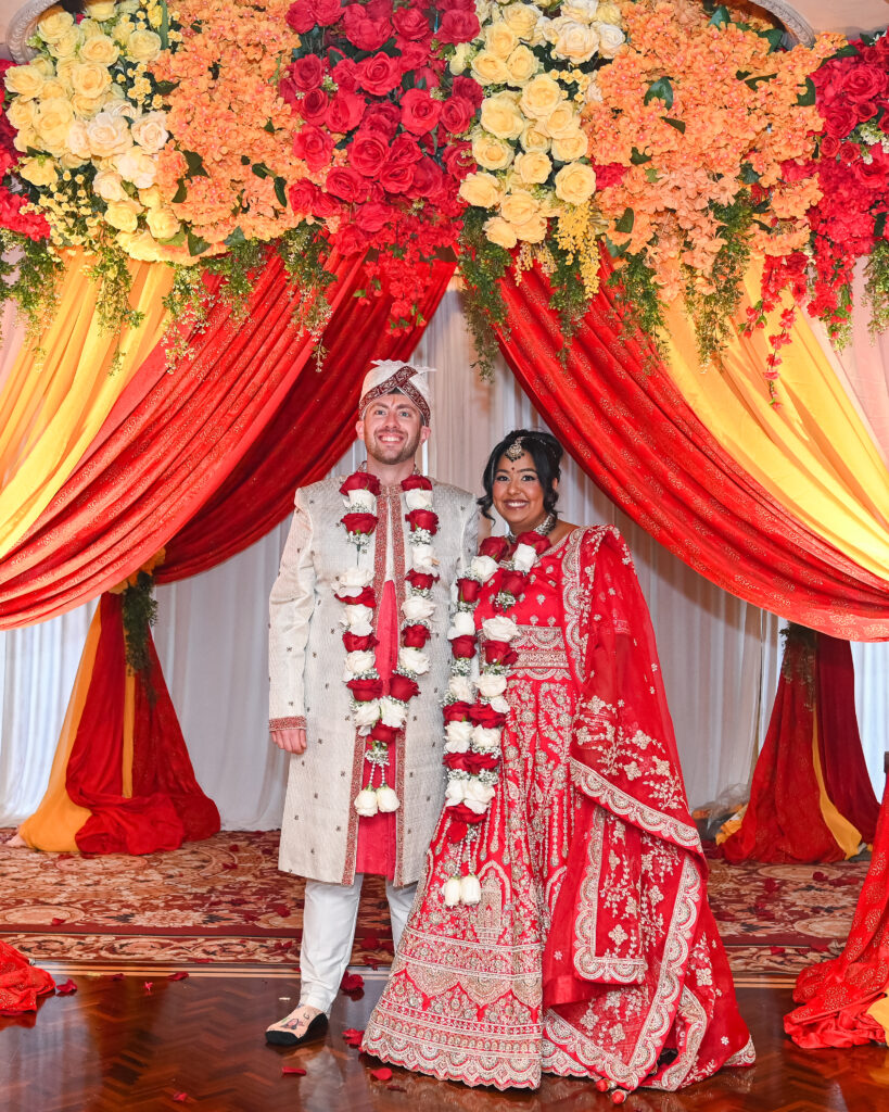 Bride and groom seated under floral mandap at Westbury Manor Long Island