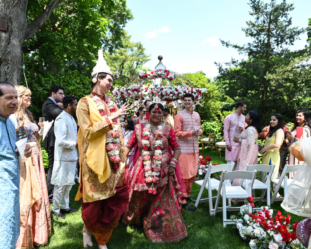 South Asian wedding guests walking through Westbury Manor gardens Long Island