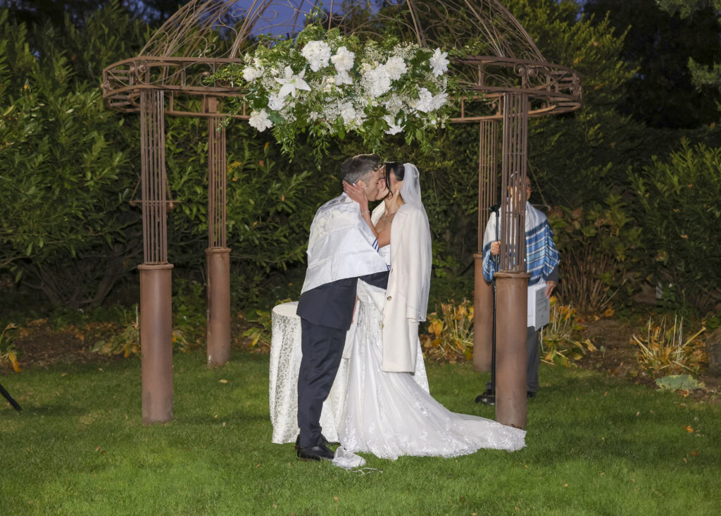 Bride and groom kissing under pergola at Westbury Manor Long Island wedding