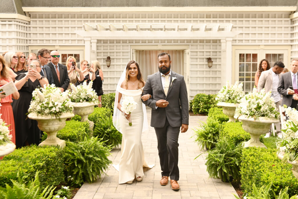 Bride and groom walking down garden aisle at Westbury Manor Long Island