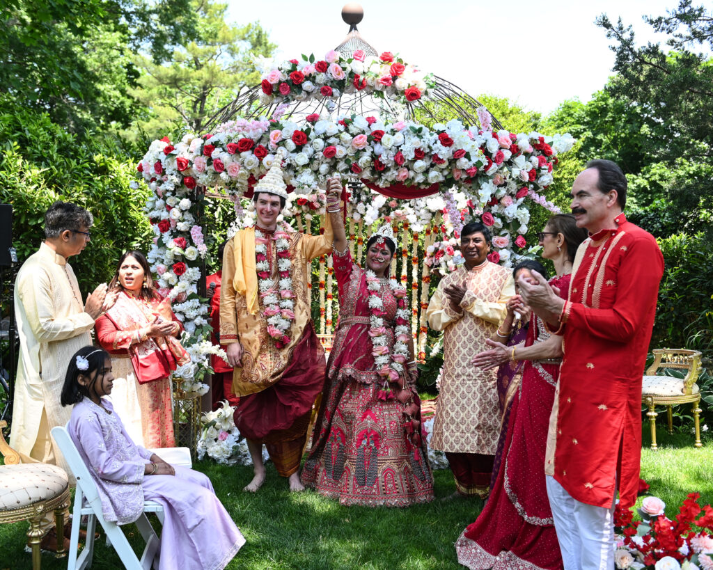 South Asian wedding ceremony under floral mandap in Westbury Manor gardens