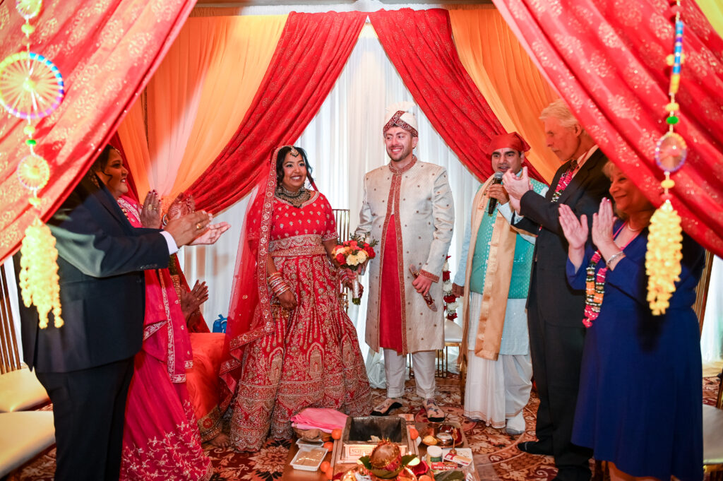 South Asian wedding ceremony under red floral mandap at Westbury Manor Long Island